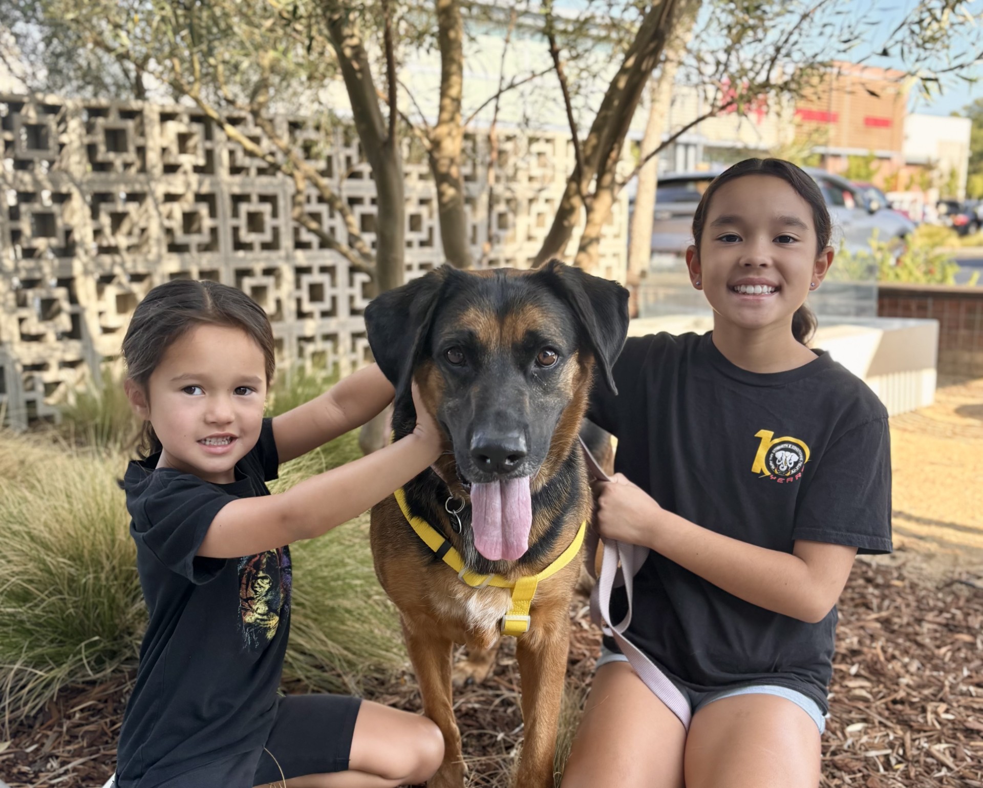 Two children with a dog smiling